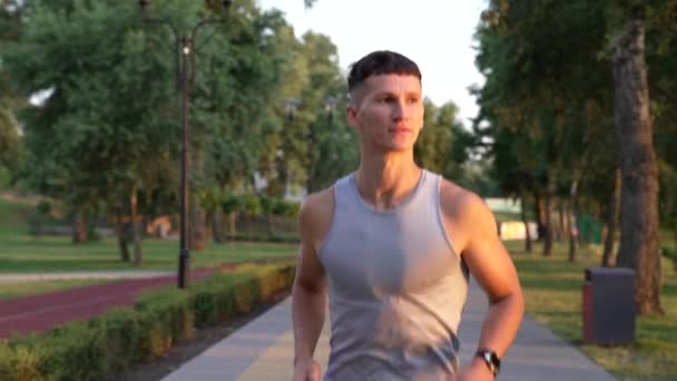muscular man sprinter running in the evening outdoor facing sunset, sport exercise - Filmati, video