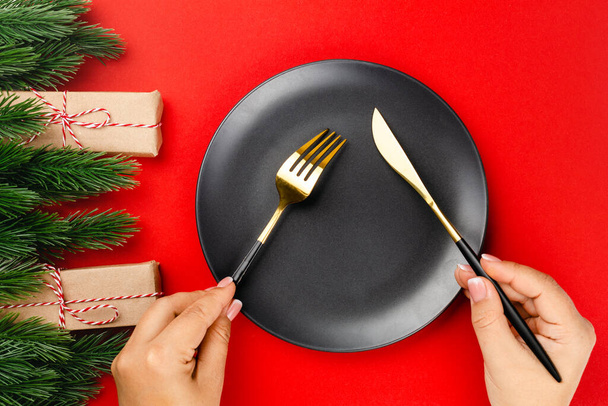 gold cutlery with black handles crossed over black plate on red table, the concept of New Year dinner - Foto, immagini