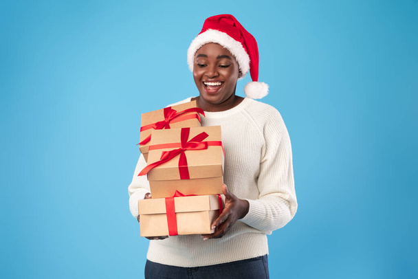 黒の女性が青い背景にクリスマスを祝うプレゼントを開催 - 写真・画像