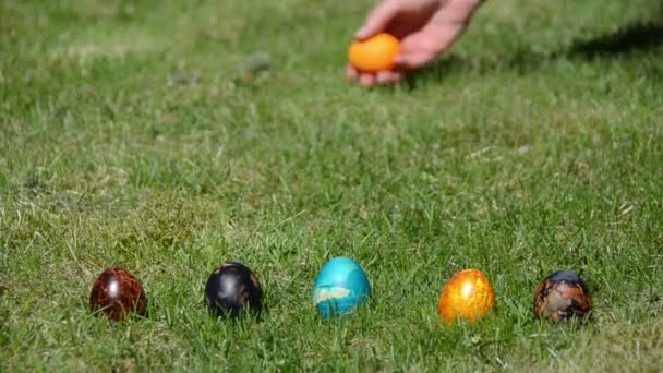 Tradicional juego de Pascua. Mano lanzar rollo de huevos de colores en la hierba
. - Imágenes, Vídeo
