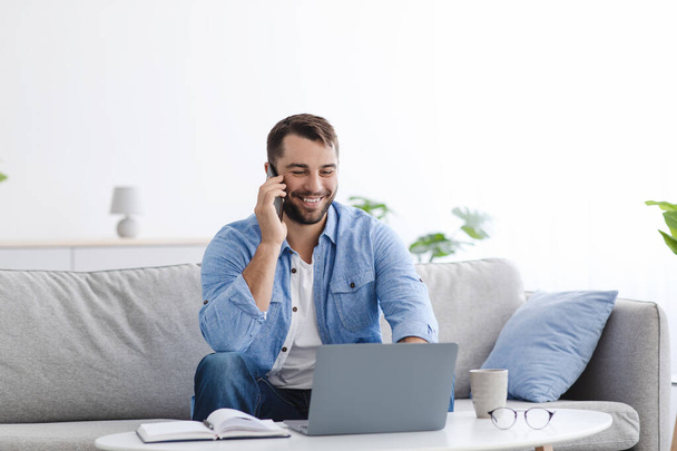 Veselý dospělý běloch manažer mají hovor, pracuje na notebooku v obývacím pokoji - Fotografie, Obrázek