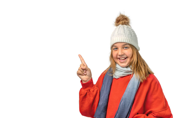 Winter portrait of a child in a hat and a red sweater shows a finger in the copy space isolated on a white background - Photo, Image