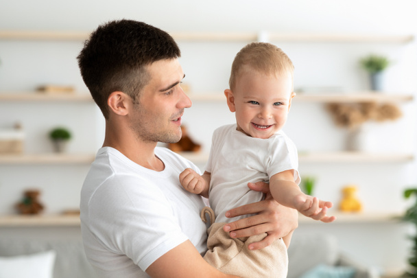 Father And Baby. Happy Young Dad Holding Adorable Toddler Child At Home - Photo, Image