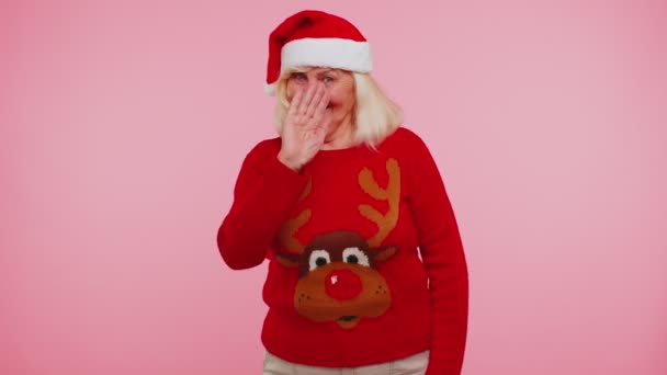 Grandmother woman in Christmas sweater with deers waves hand palm in hello gesture welcomes someone - Footage, Video