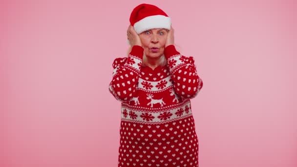 Senior grandmother woman in Christmas clothing covering ears, gesturing no, avoiding advice ignoring - Footage, Video
