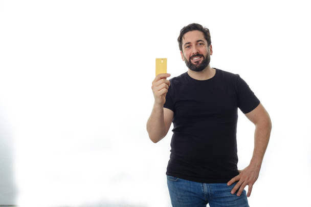 Porträt eines Mannes, der eine Kreditkarte hält, während er auf einem isolierten Hintergrund steht. - Foto, Bild