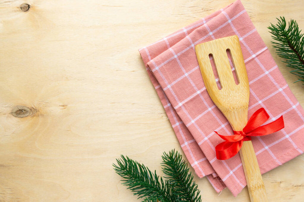 Christmas composition. Kitchen spatula and towel on wooden background, space for text - Foto, Imagem