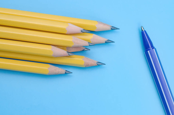 Una pluma azul y un montón de lápices amarillos sobre fondo azul. Concepto de individualidad y diferencia. - Foto, imagen