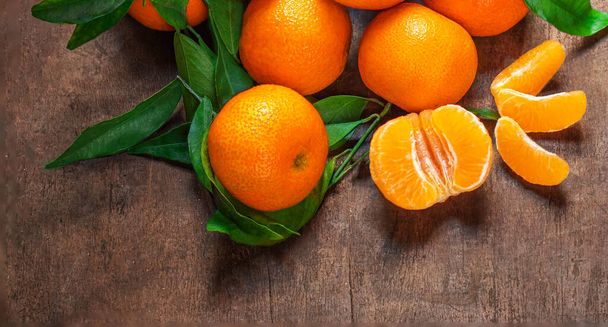 Sweet Mandarines oranges fruits or tangerines with green leaves on a wooden table. Copyspace. Fresh picked mandarins Top view.  - Foto, imagen