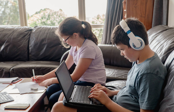 Fratello e sorella seduti in salotto a fare scuola a casa e online - Foto, immagini