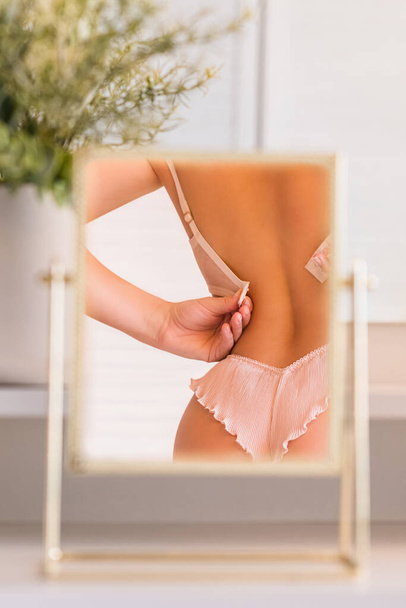 Reflection in table mirror of woman body in underwear on dressing table with make up accessories. Vertical ratio - Foto, Bild