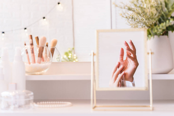 Reflection in table mirror of woman hand  on dressing table with make up accessories. Self-Care.  - Photo, Image