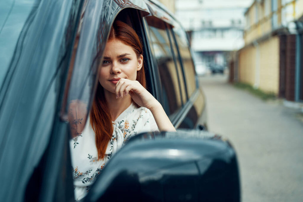 cheerful woman driving a car looks out of the window - Fotografie, Obrázek