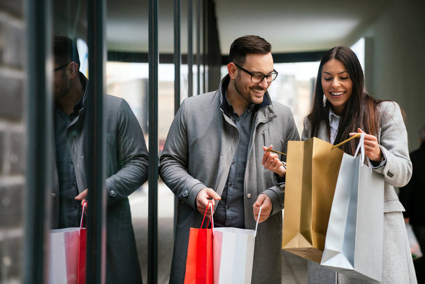 Beautiful young couple carrying bags and enjoying together the Christmas shopping. Sale people concept - Photo, image