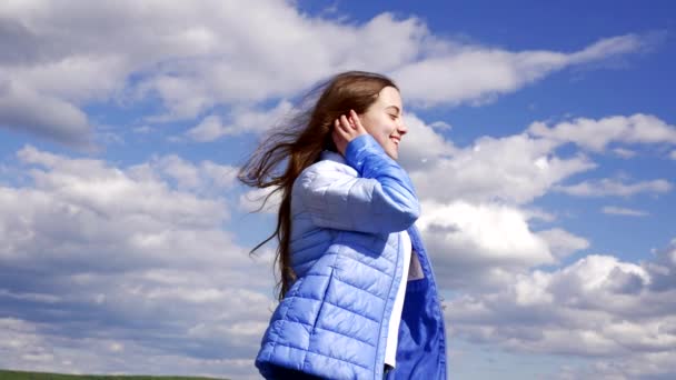 gelukkig kind in de herfst jas poseren op lucht achtergrond, haar - Video