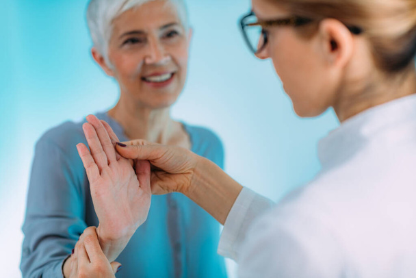 Az orvos kéztőalagút szindróma tesztet végez egy idős nővel. - Fotó, kép