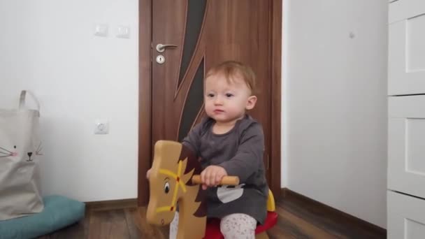 Happy baby girl playing on wooden rocking horse. Childhood, game at home concept - Footage, Video