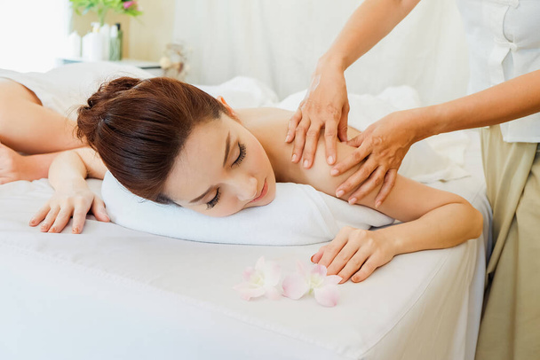 Jovem mulher asiática relaxante no spa massagem mentira em seu estômago na cama - Foto, Imagem