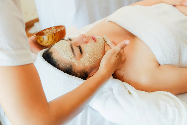 mujer asiática que tiene tratamiento facial en el salón de spa en la cama, máscara facial natural de belleza - Foto, Imagen