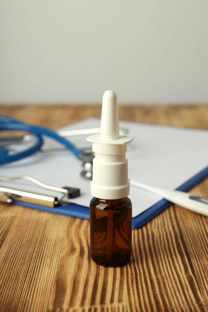 Nosní sprej, stetoskop, teploměr a schránka na dřevěném stole - Fotografie, Obrázek
