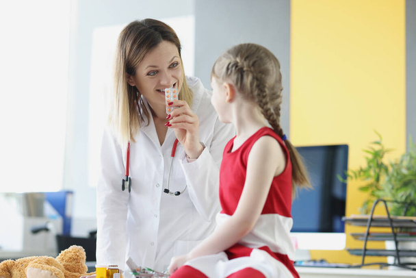 Ärztin zeigt kleine Mädchen Blase mit Medikamenten in Klinik - Foto, Bild