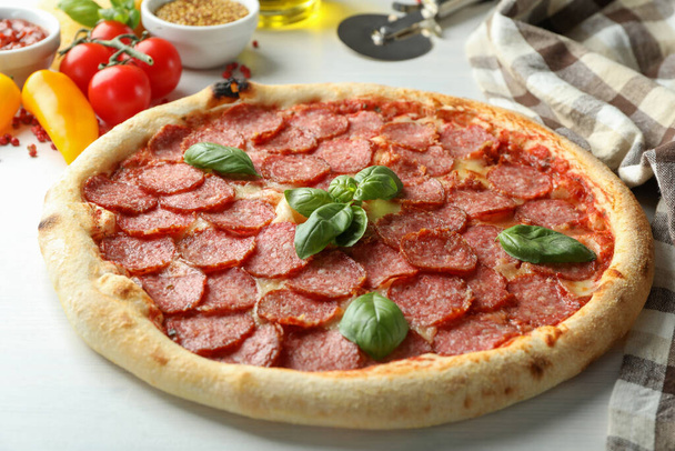 Concept de nourriture savoureuse avec pizza au salami sur fond de bois blanc - Photo, image