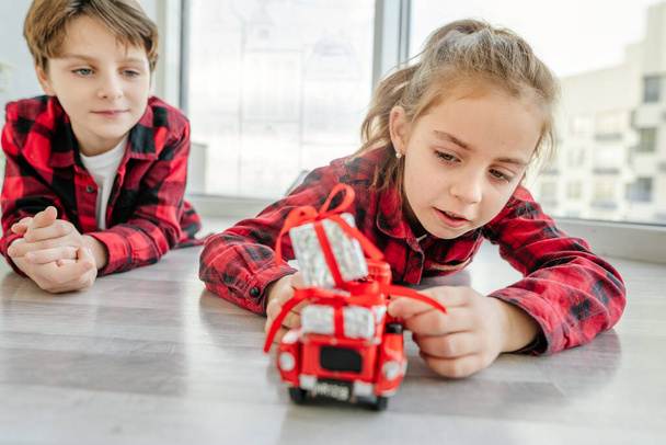 Dzieci bawiące się czerwonym samochodem zabawki i pudełka świąteczne. - Zdjęcie, obraz
