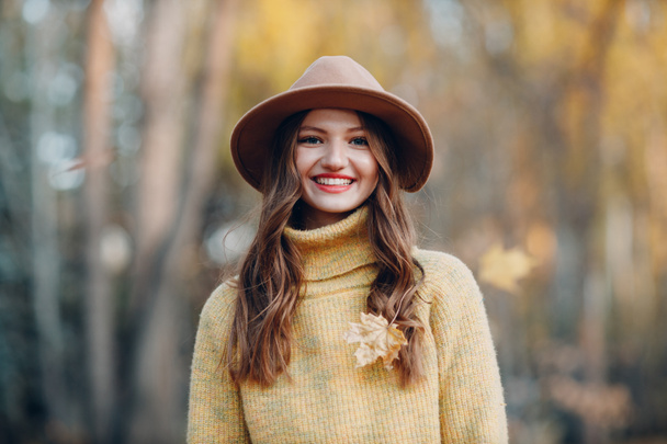 Junge Frau modelliert im Herbstpark mit gelben Blättern von Ahornbäumen. Herbstmode. - Foto, Bild
