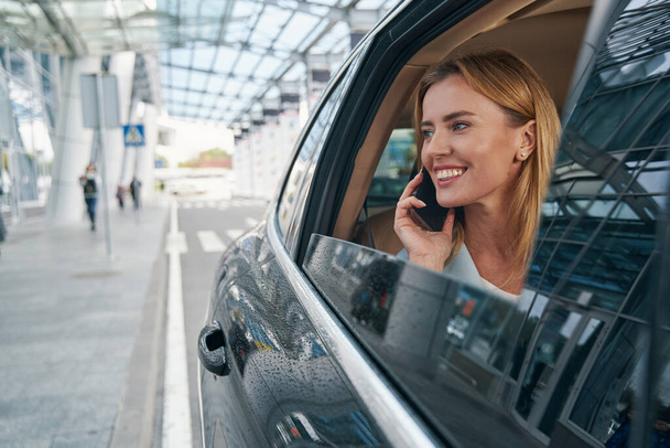 Joyful young car passenger talking on cellphone - Fotó, kép