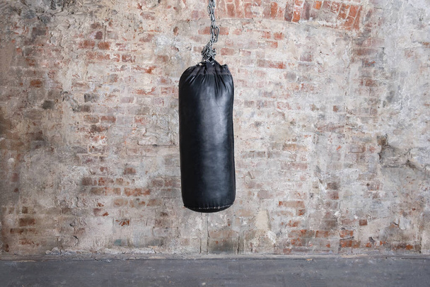 Black punching bag with grunge brick wall with blank space - Fotografie, Obrázek