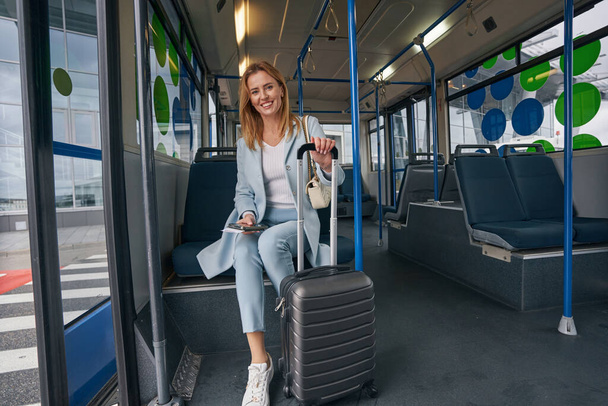 Pleased stylish traveler posing for camera in airport shuttle bus - Zdjęcie, obraz