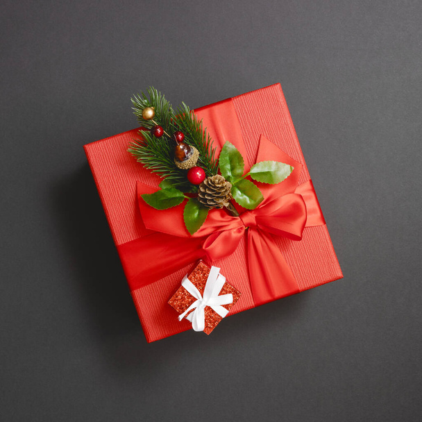 A tiny red box stands on top of a larger gift box decorated with a spruce branch. Top view - Foto, afbeelding