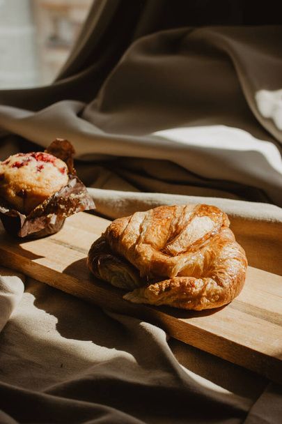 Egy közeli kép croissant és muffin egy fa fórumon - Fotó, kép