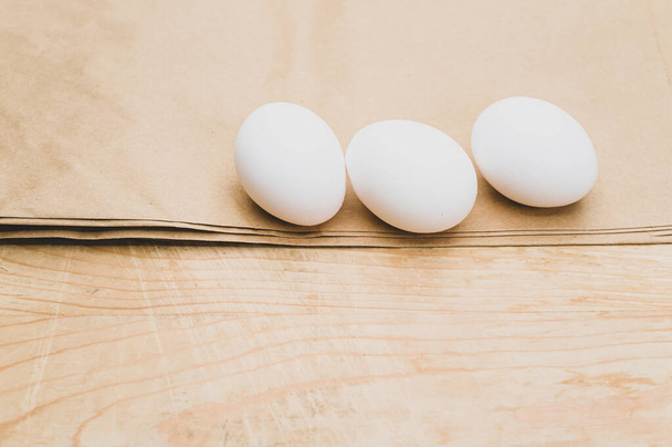 organic white eggs on a natural wooden and brown paper background with copy space for text - Fotoğraf, Görsel