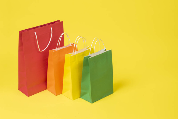 A closeup shot of colorful shopping bags on a yellow background - Foto, Imagen