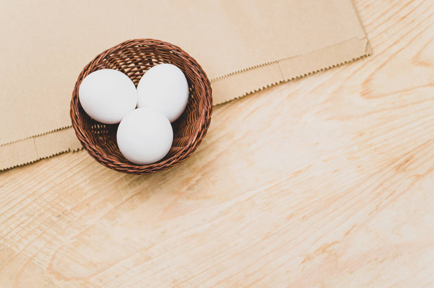 organic white eggs in a canister on a natural wooden and paper background with copy space for text - Фото, зображення