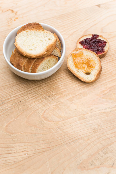 organic fresh sliced bread in a white bowl and jam on a wooden tabletop with copy space - Фото, изображение