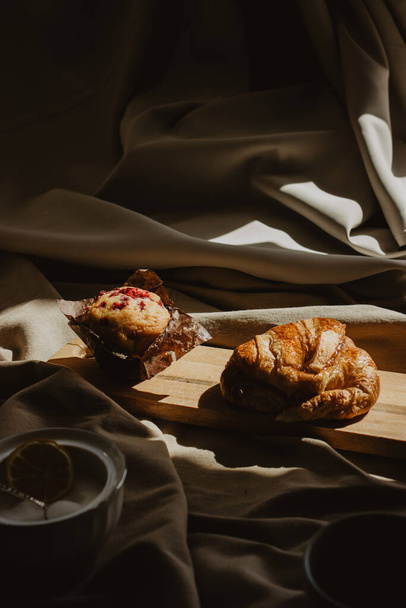 A vertical shot of varied Mediterranean breakfast of coffee beans with croissant and muffin - Фото, зображення