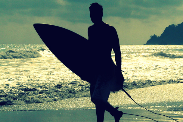 Silhouette of surfer with a board on a sunset evening in Manuel Antonio 's National Park main beach, Costa Rica
 - Фото, изображение