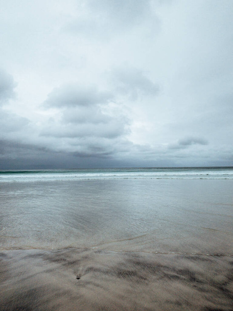 An empty white sand beach on a cloudy day - Фото, изображение