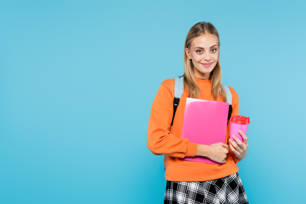 Positive student with backpack holding laptop and coffee to go isolated on blue  - Foto, Bild