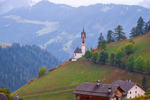 Santa Barbaran kirkko viihtyisässä La Vallen kylässä sumuisena aamuna, Alta Badia, Etelä-Tiroli Italiassa, Euroopassa - Valokuva, kuva