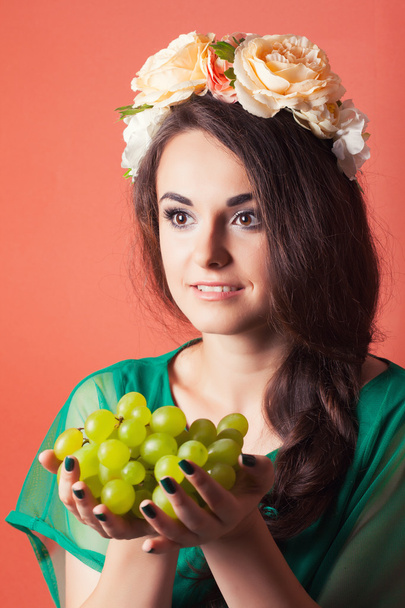 Young woman wearing wreath and holding green grapes - Foto, immagini