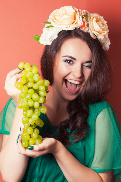 Young woman wearing wreath and holding green grapes - Foto, Imagem