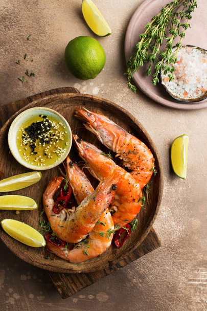 Fried tiger prawns with lime. Seafood with thyme on a wooden plate. Shrimp with sauce. - Photo, Image