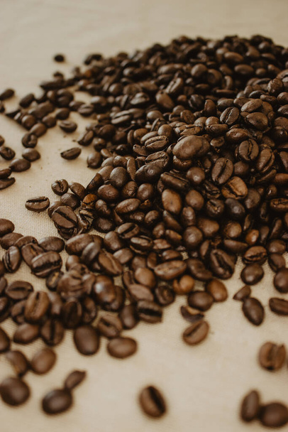Een verticaal shot van koffiebonen geïsoleerde beige stof achtergrond - Foto, afbeelding