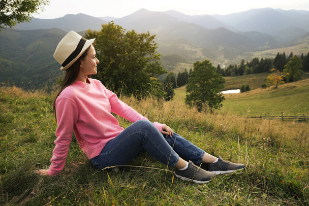 Young woman enjoying beautiful view of mountain landscape - Zdjęcie, obraz