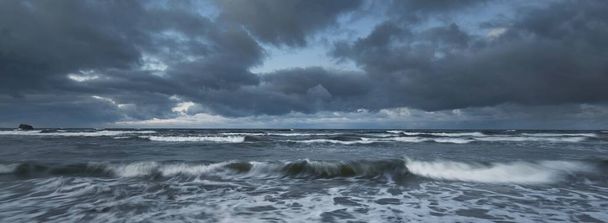 Gewitterwolken über der Ostsee im Winter, lange Belichtung. Dramatischer Himmel bei Sonnenuntergang, Wellen und Wasserspritzer. Dunkle Seelandschaft. Deutschland - Foto, Bild