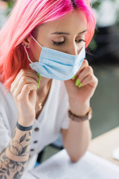 tattooed manager with pink hair wearing medical mask in office - Foto, Bild