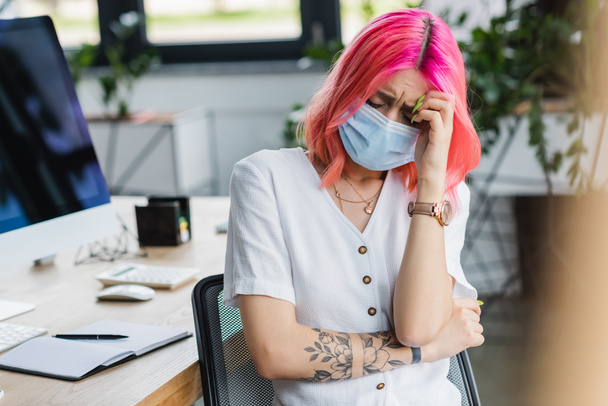 donna d'affari tatuata in maschera medica con mal di testa in ufficio - Foto, immagini